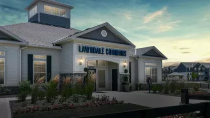 The Lawndale Commons clubhouse illuminated at dusk, showcasing its inviting exterior, lush landscaping, and modern architectural design.