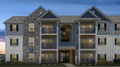 A Lawndale Commons apartment building at twilight, with warm interior lights glowing from the windows, enhancing its cozy and sophisticated appeal.