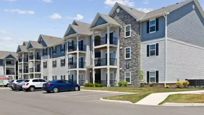 A spacious parking lot in front of Lawndale Commons' three-story apartment buildings, featuring private balconies and stylish exterior finishes.