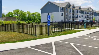 A designated accessible parking space with a nearby fenced green area at Lawndale Commons, ensuring convenience for all residents.