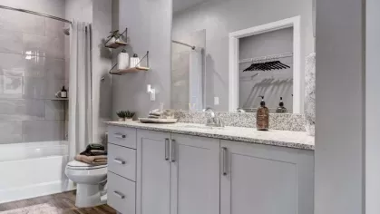 Spacious bathroom with stylish lighting, a large mirror, and built-in storage, complemented by contemporary shelving and elegant décor.