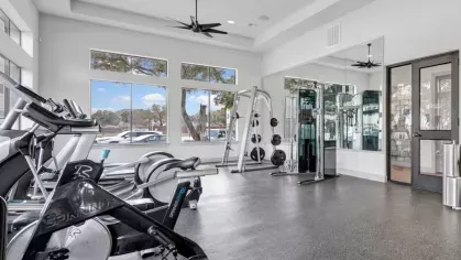Fully equipped gym with cardio machines, strength training equipment, and ceiling fans, providing a high-end fitness experience for residents.