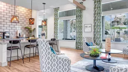 Contemporary clubhouse featuring an open floor plan, chic seating, and an accent-tiled kitchen, ideal for community interaction and events.