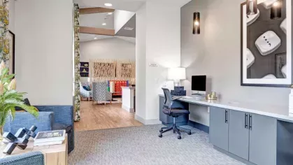 Business center with a sleek workspace, modern lighting, and comfortable seating, providing a quiet and productive environment for residents.