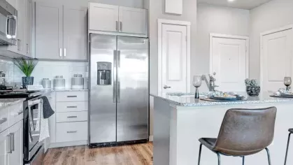 Contemporary kitchen with a sleek design, featuring granite countertops, stainless steel appliances, and a cozy breakfast bar with leather stools.