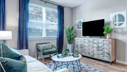 A bright and inviting living space with a cozy sofa, bold accent pillows, and a decorative console under a mounted TV, blending comfort with modern style.