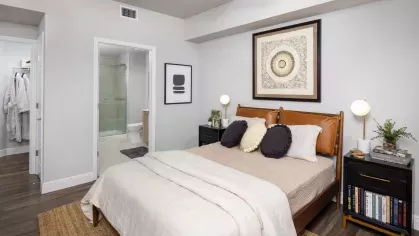 A luxurious bedroom featuring a cozy upholstered bed, modern lighting, and direct access to a sleek, spa-inspired bathroom.