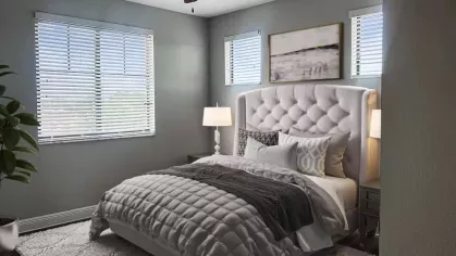 Sophisticated bedroom at Locklyn West Palm, featuring a leather-upholstered bed, plush pillows, and elegant decor. Large windows offer a scenic view of the community.