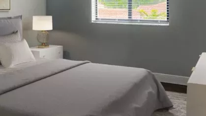 Cozy bedroom retreat with a plush white bed, soft lighting, and wooden furniture. The soothing color palette and decorative accents create a peaceful sanctuary.