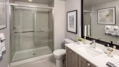 Modern bathroom featuring a glass-enclosed shower, sleek vanity with ample storage, and stylish framed artwork. Neutral tones and elegant fixtures create a spa-like ambiance.