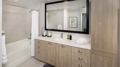 Modern bathroom featuring a glass-enclosed shower, sleek vanity with ample storage, and stylish framed artwork. Neutral tones and elegant fixtures create a spa-like ambiance.