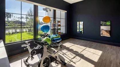 A well-equipped gym at Locklyn West Palm, offering high-end cardio machines, strength training stations, and expansive windows overlooking lush greenery.