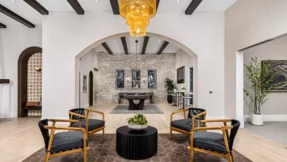 The stylish resident lounge at Locklyn West Palm, featuring a grand chandelier, cozy seating areas, and a billiards table under elegant archways.