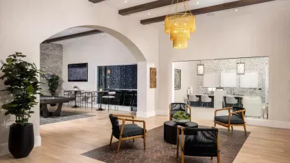 A beautifully designed clubhouse with high ceilings, modern furnishings, and an open layout that includes a social lounge and workspaces.