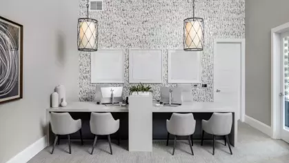 A sophisticated leasing office at Locklyn West Palm, featuring a sleek white desk, plush seating, and designer pendant lighting.