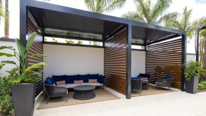 Stylish outdoor cabanas with plush seating and modern slatted wood panels, offering shade and privacy in a tropical setting.