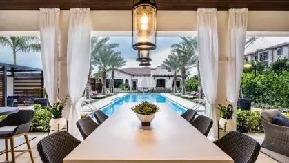 A covered outdoor seating area with a stylish dining table, overlooking the shimmering resort-style pool at Locklyn West Palm.