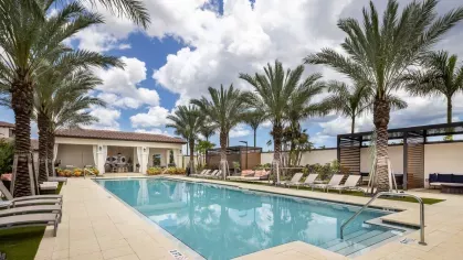 A sunlit pool area at Locklyn West Palm, complete with plush loungers, shaded cabanas, and a tranquil, upscale atmosphere.