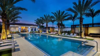 The resort-style pool at Locklyn West Palm glows under soft evening lighting, with poolside cabanas and tropical landscaping creating a serene retreat.