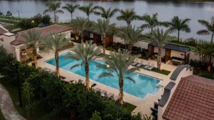 Aerial perspective of the Locklyn West Palm pool deck, featuring private cabanas, lush palm trees, and a lakefront setting for a tranquil escape.