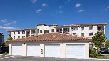 Secure private garages with Mediterranean-inspired apartment buildings in the background, offering modern living with convenience at Locklyn West Palm.