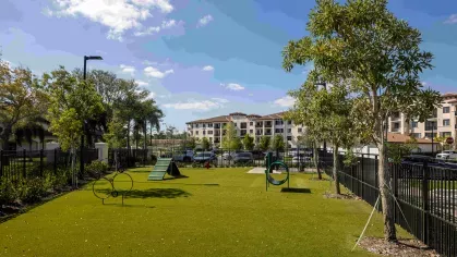 A vibrant dog park with lush landscaping, agility training equipment, and ample space for pets to exercise in a secure environment.