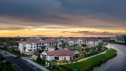 A wide-angle aerial view of Locklyn West Palm’s resort-inspired community, featuring elegant residential buildings, waterfront walking trails, and beautifully designed outdoor spaces.