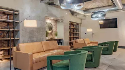 Comfortable community space with leather and green armchairs, accent lighting, and modern decor.
