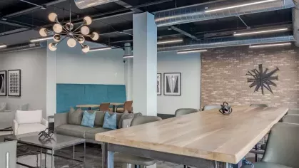 Communal space with a long wooden table, modern lighting, and a mix of seating options.
