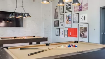 Game room featuring two pool tables, modern pendant lighting, and eclectic wall art.
