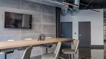 Collaborative work area with a high table, barstools, and a wall-mounted TV.