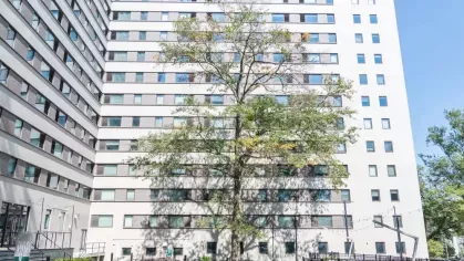Exterior view of a tall modern apartment building with a landscaped courtyard.