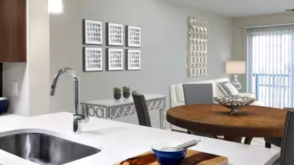 A contemporary kitchen with stainless steel appliances, wood cabinetry, and a quartz countertop island, leading into a stylish dining area.