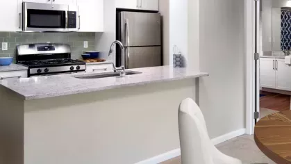 A stylish open-concept living and dining space featuring a spacious kitchen, round dining table, and modern décor with warm, neutral tones.