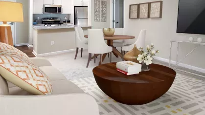 A well-appointed kitchen with white cabinetry, stainless steel appliances, and a spacious breakfast bar overlooking a bright living and dining area.