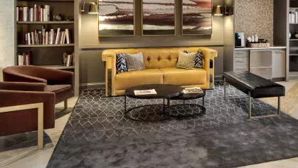 A modern resident lounge with plush seating, a stylish area rug, and a sleek marble-topped bar with pendant lighting, creating a warm and inviting communal space.