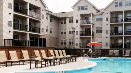 The Mark at Mamaroneck’s pool deck featuring rows of plush lounge chairs and modern apartment buildings in the background.