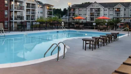 A twilight view of the pool area at The Mark at Mamaroneck, illuminated by warm sunset hues and glowing community lights.