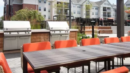 A contemporary outdoor space with shaded seating, modern grills, and beautifully landscaped surroundings.