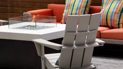 A contemporary fire pit with a glass enclosure, surrounded by comfortable outdoor seating, offering a cozy retreat for residents.