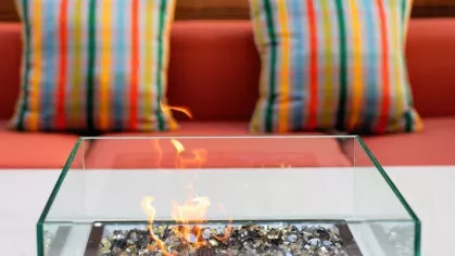 A chic outdoor seating area with a modern fire pit, colorful striped pillows, and a warm ambiance for relaxation.