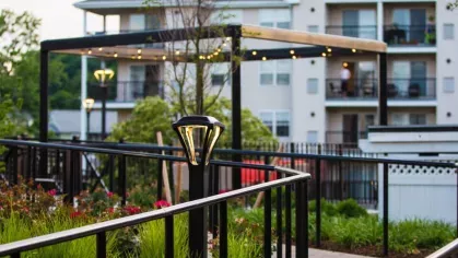 A well-maintained garden pathway with soft lighting leading to a pergola-covered seating area, creating a serene and inviting outdoor space.