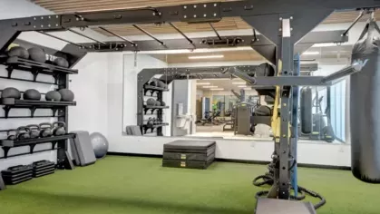 A functional training area featuring a turf floor, suspension trainers, a boxing bag, and racks of kettlebells and medicine balls.