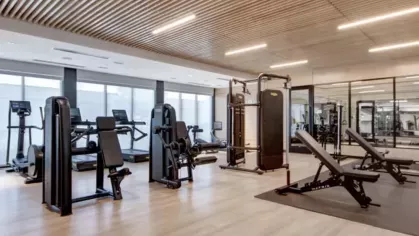 A spacious gym with various weight machines, treadmills, and strength-training benches illuminated by overhead lighting.