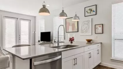 A bright open-concept living space with a large kitchen island, pendant lighting, and contemporary decor.