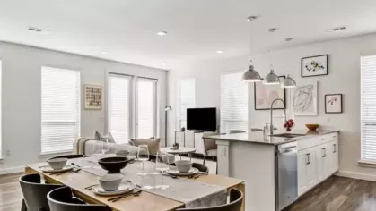 A dining and living area with a wood dining table, black chairs, and an open kitchen layout.