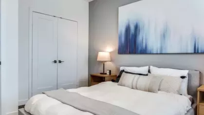 A minimalist bedroom with a modern bed, neutral bedding, and soft lighting from bedside lamps.