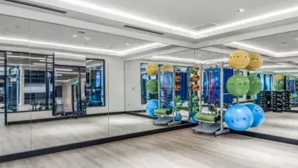 A well-lit fitness studio with mirrored walls, colorful exercise balls, and an open workout space.