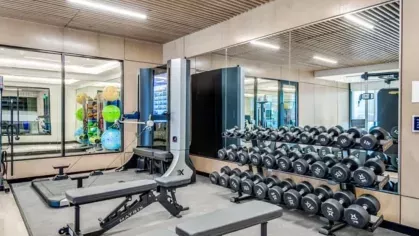 A high-end gym with a dumbbell rack, weight benches, and sleek modern workout equipment.