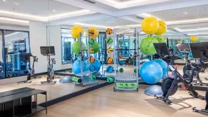 A bright and airy gym with stationary bikes, weight racks, and vibrant exercise balls.